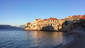 Un bâtiment situé sur la côte, doté de nombreux balcons et d’une façade en pierre, et qui donne sur un plan d’eau.