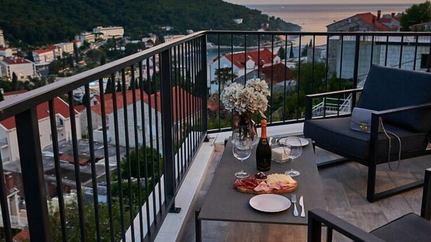 A balcony with a table set for a meal, a chair, and a vase of flowers. - Apartment Blù-Two Bedroom Apartment with Terrace and Sea View (Dubrovnik)