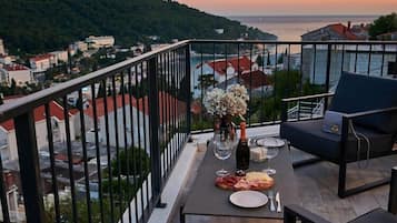 Un balcon avec une table dressée pour un repas, une chaise et un vase de fleurs.
