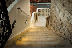 Staircase leads upwards, flanked by a white and stone wall.