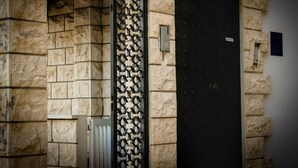 A stone building with a black door and a decorative metal gate.