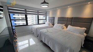 Una moderna camera d'hotel con due letti, un'ampia finestra vista città, un ventilatore a soffitto e un pavimento in marmo.