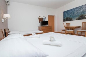 Een hotelkamer met twee bedden, een bureau, een stoel, een televisie en een schilderij aan de muur.