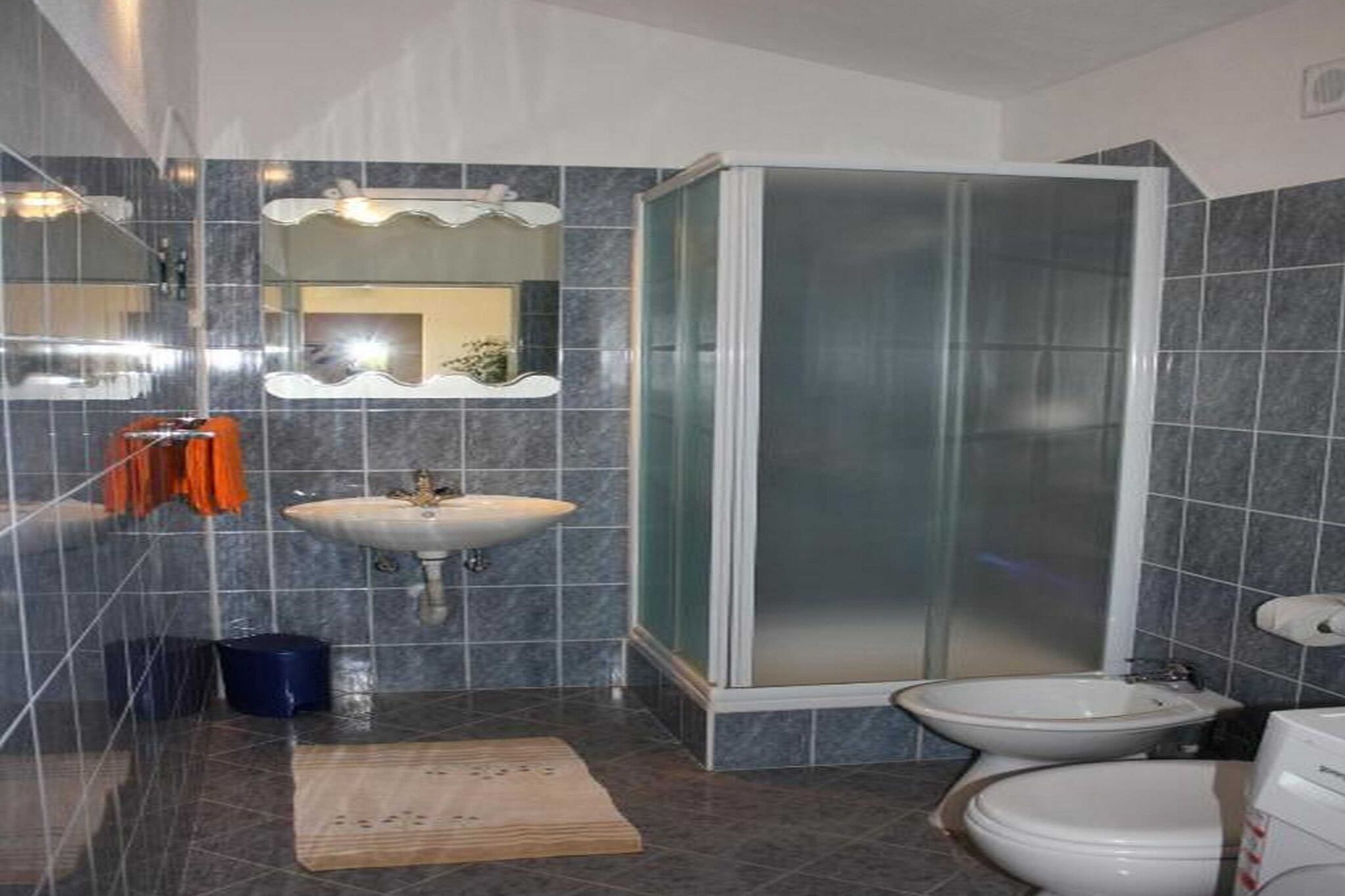 Une salle de bain équipée d’un lavabo, d’un miroir, d’une douche et de toilettes.