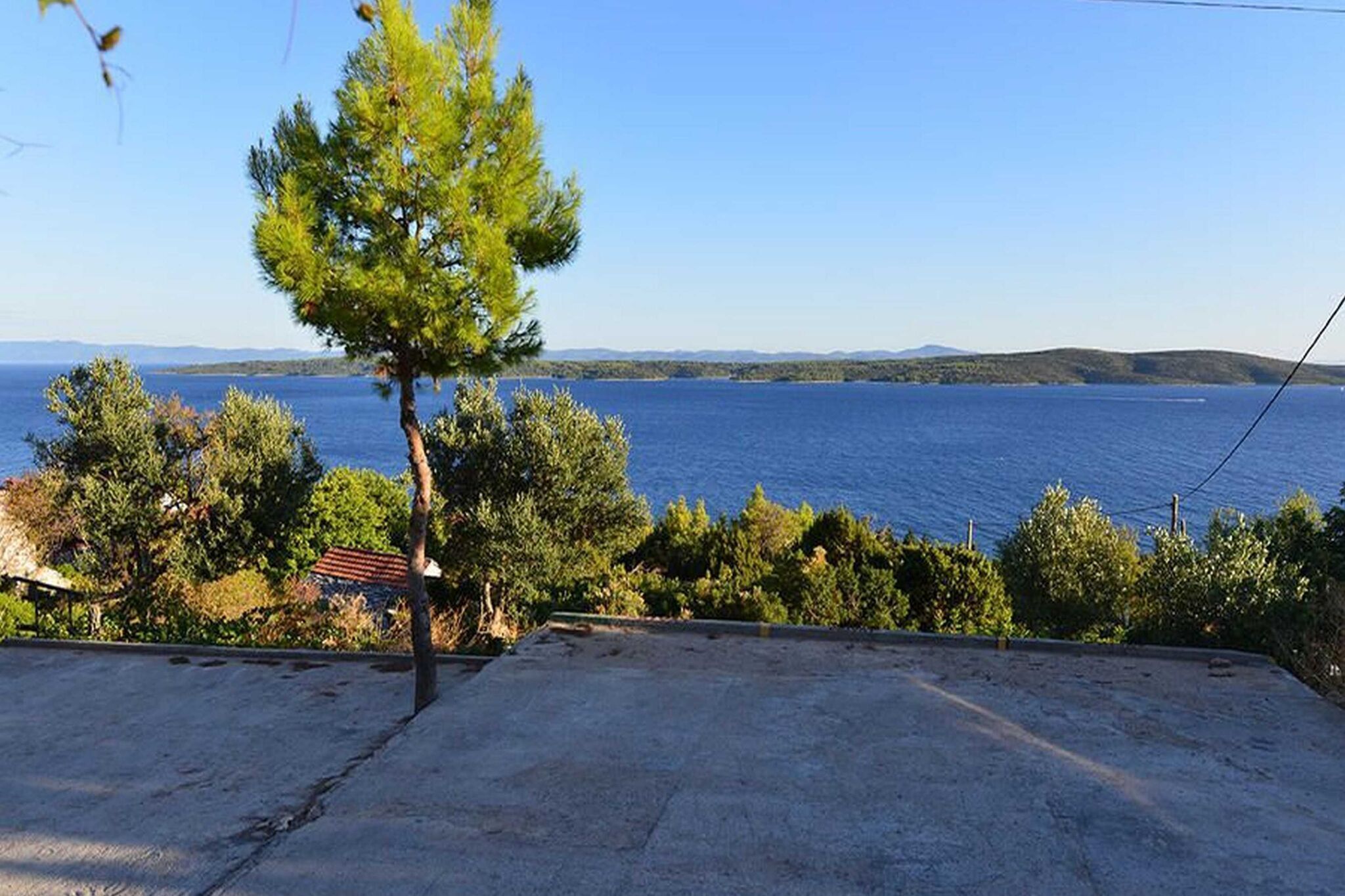 A concrete terrace with a view of a lake and distant hills.