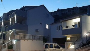 Ein zweistöckiges Wohnhaus mit Balkonen und einer Garage, vor der ein weißer Lieferwagen geparkt ist.