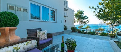 Un espacio exterior moderno con una mesa de vidrio, un sofá y una planta en maceta.