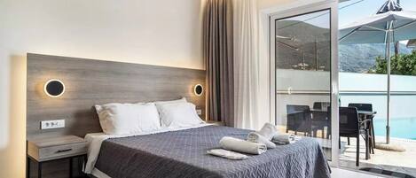 Habitación de hotel moderna con una cama grande, una mesita de noche y una puerta de cristal que da a un área exterior con piscina y sillas.