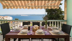 Une table à manger dressée pour quatre personnes, avec vue sur la mer.