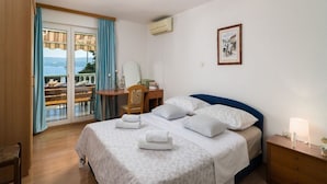 Une chambre à coucher avec un lit, un bureau, une chaise et une vue sur l’extérieur.