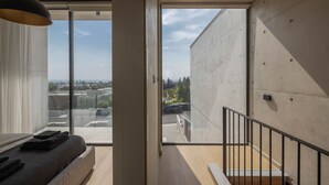 A modern interior with a large sliding glass door leading to a balcony with a city view. - Designer Townhouse with heated infinity pool in Paphos (Chlorakas)