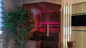 Une pièce avec un meuble en bois, une plante en pot et une cloison en verre éclairée de lumière rouge.