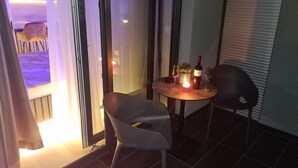 Une petite pièce à la lumière tamisée, avec une table dressée pour deux personnes, une chaise et une bouteille de vin.