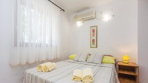 Une chambre à coucher avec un lit, une table de chevet avec une lampe et un appareil de climatisation fixé au mur.