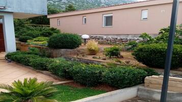 A residential building with a garden featuring various plants and a stone wall.