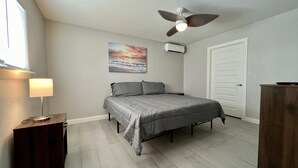 A bedroom with a bed, a ceiling fan, a painting, a door, and a nightstand. - Miramar #4 - Gorgeous and Spacious 3BD/2BA - WiFi (Brownsville)