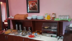 Un bufé de desayuno con diferentes opciones de comida, una máquina de café y un dispensador de jugo.