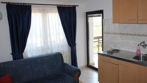 Una sala de estar con sofá y comedor con barra de cocina y alacenas.