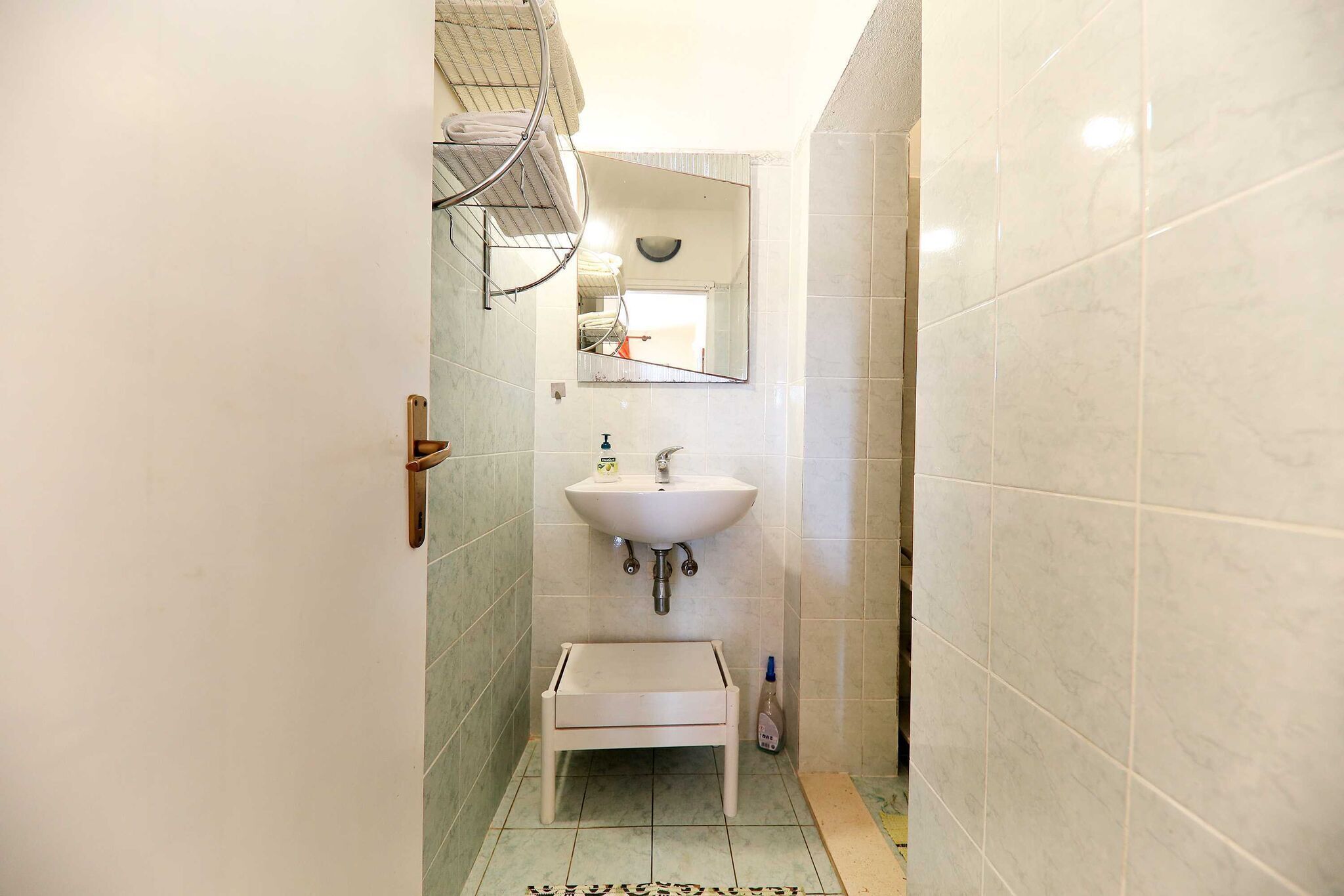 Un bagno piccolo con un lavandino bianco, uno specchio e un portasciugamani.
