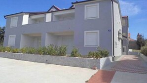 Un edificio residencial de dos plantas con techo plano, paredes exteriores blancas y un pequeño porche delantero.