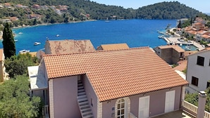 Un pueblo costero con edificios de tejados de terracota, un puerto deportivo y una vista despejada del mar.