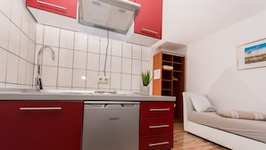 Una cocina moderna con armarios rojos, lavavajillas y salpicadero de azulejos.