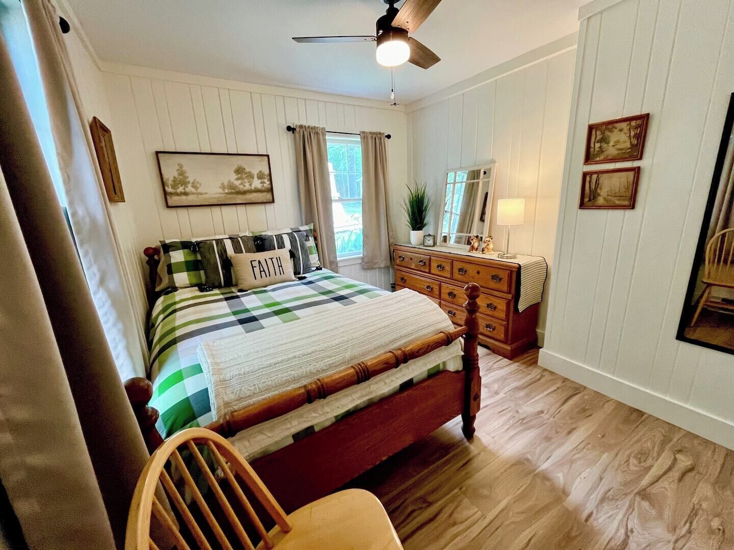 Une chambre à coucher avec un lit en bois, une commode, une chaise et un ventilateur de plafond.