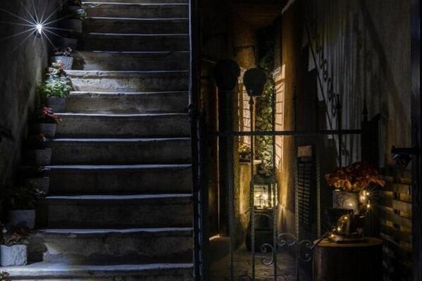 A staircase with stone steps and a metal gate leading to a warmly lit interior space with a fireplace and decorative items. - History House Moja Ti 1830 - Deluxe Apartment (Gorica) (Senj)