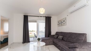 A modern living room with a grey sofa, a white coffee table, and a pendant light.