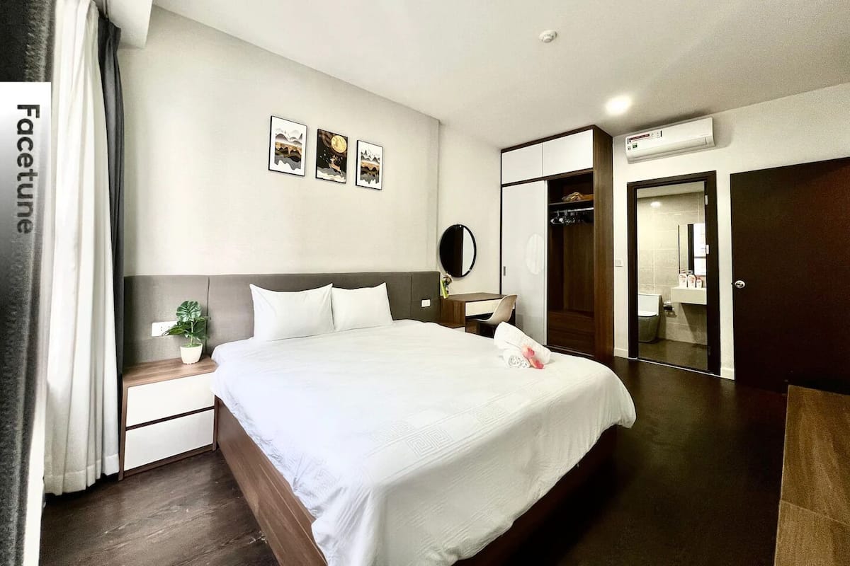 A hotel room with a large bed, a bedside table with a plant, a mirror, and a wardrobe.