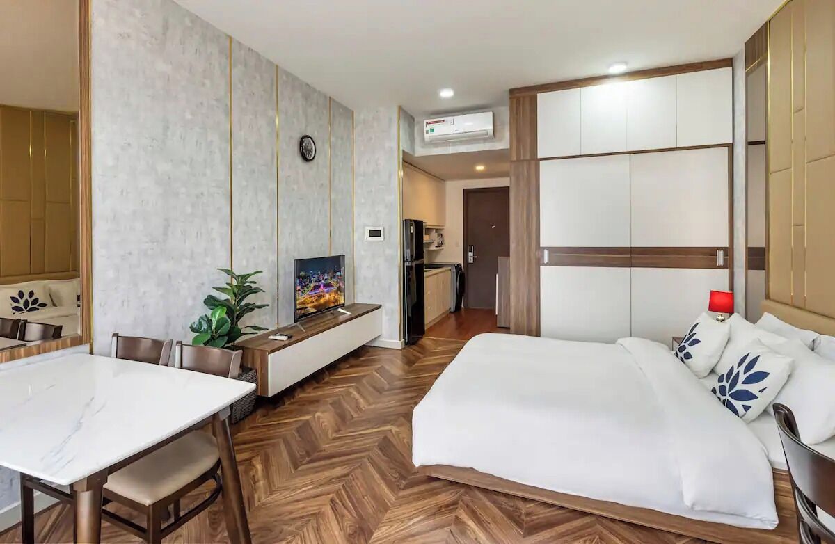 Een hotelkamer met een groot bed, een eettafel, een televisie en een kitchenette.