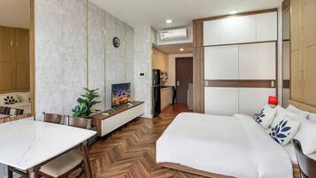 Een hotelkamer met een groot bed, een eettafel, een televisie en een kitchenette.