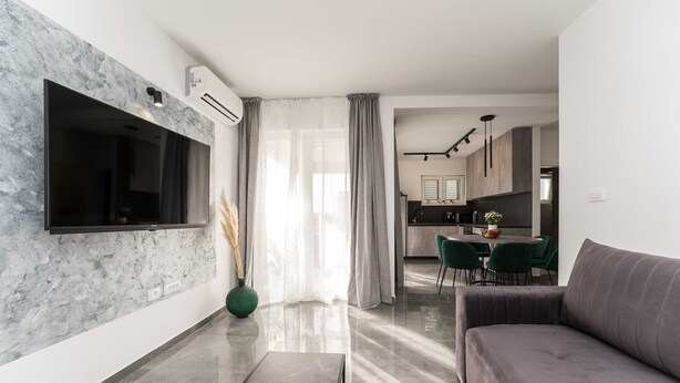Una sala moderna con una televisión de pantalla plana, un sofá, una mesa de centro y un comedor con sillas y una mesa.