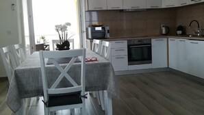 A modern kitchen with white cabinets, a microwave, a kettle, and a dining table with chairs. - Apartment Villa Bijele Stijene - Two Bedroom Apartment with Terrace and Sea View (Karlobag)