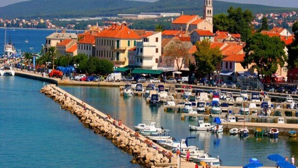 A coastal town with a marina, historic buildings, and a prominent church tower.