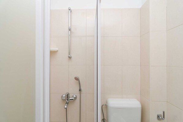 A bathroom with a glass shower enclosure, a toilet, and a wall-mounted towel rack.