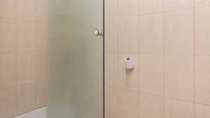 A bathroom with beige tiles, a frosted glass door, and a toilet paper holder on the wall.