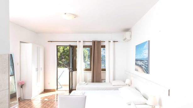 A hotel room with two beds, a desk, a chair, a laptop, and a painting on the wall.