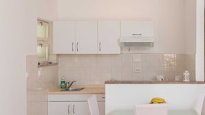 A compact kitchen with white cabinets, a built-in oven, and a countertop with a sink.