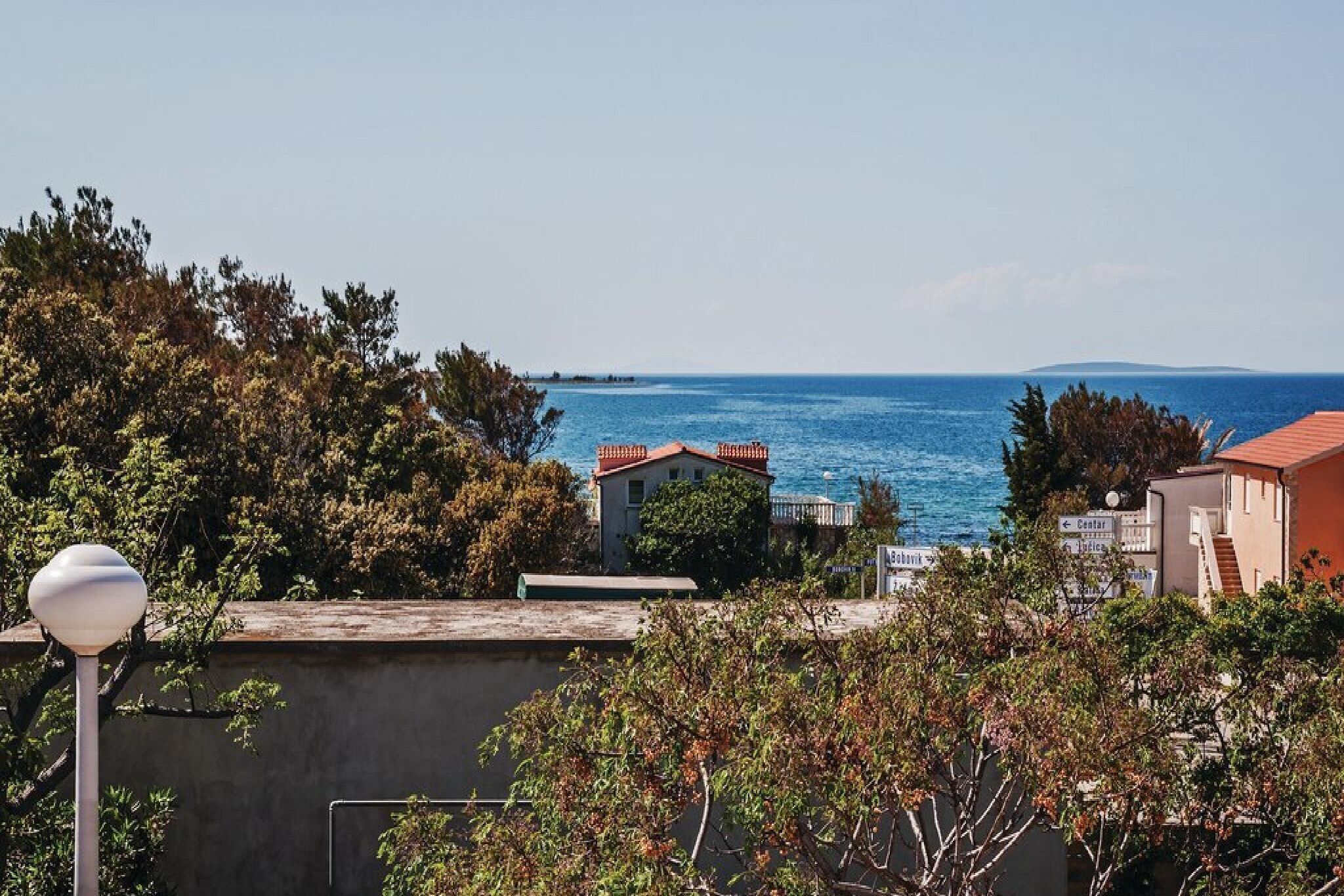 A coastal view with a building in the foreground and the sea in the background.