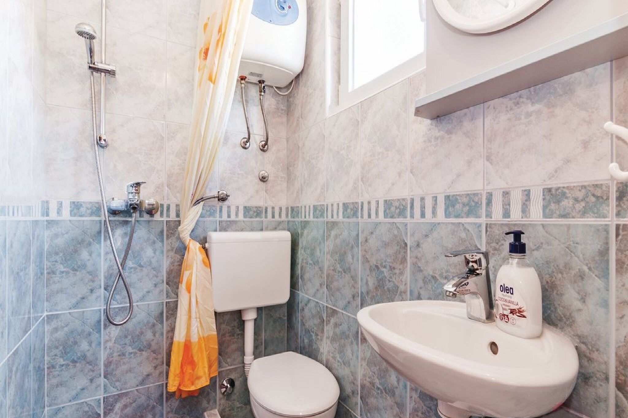 A bathroom with a toilet, sink, shower, and towel rack.