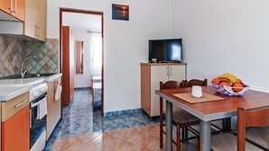 A compact kitchen with a dining area, a television, and a fruit bowl. - Apartments Hak - One Bedroom Apartment with Terrace and Sea view (Vir)