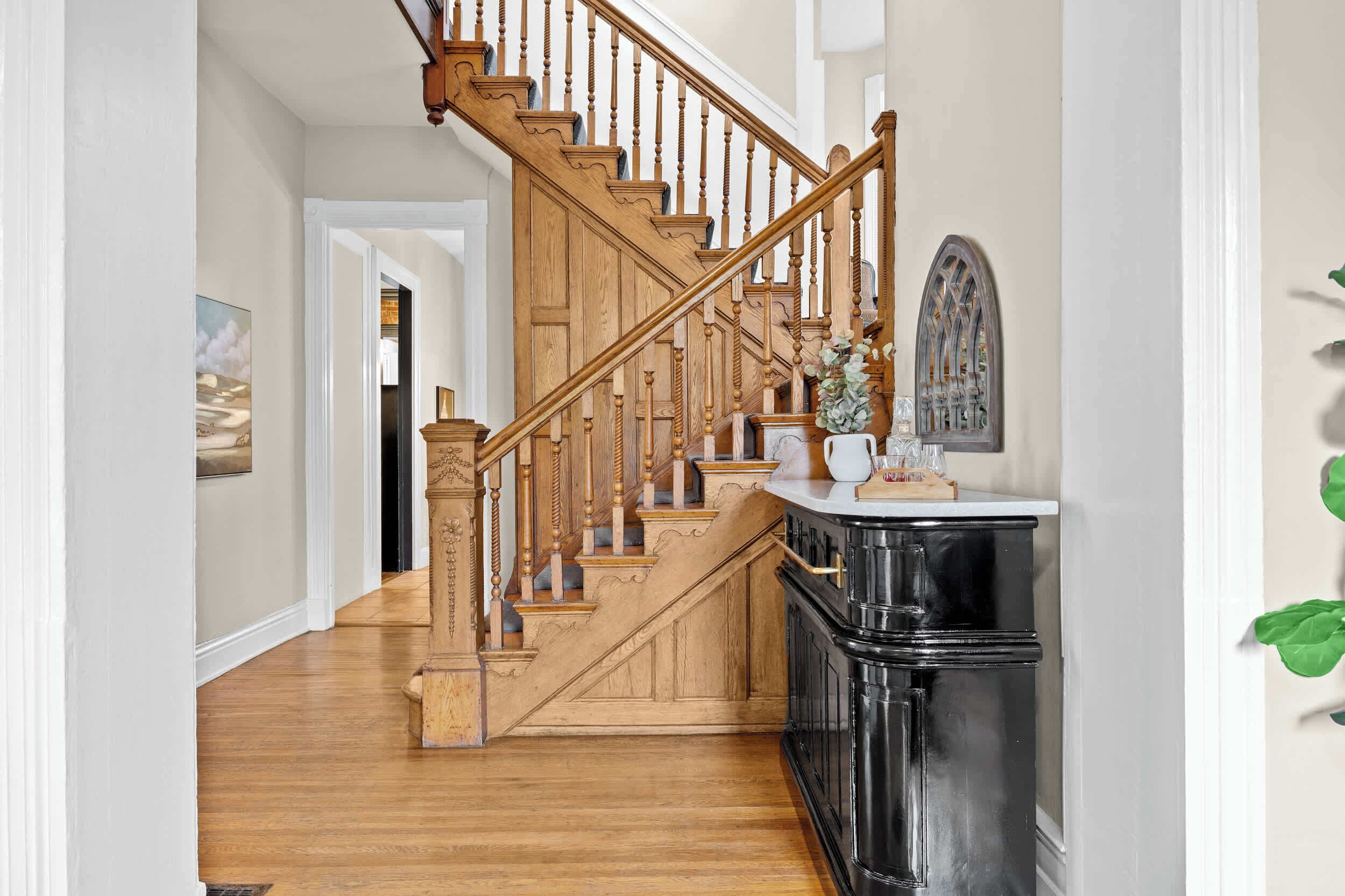 Un escalier en bois avec un meuble noir à sa base.