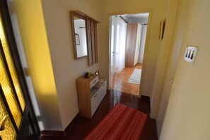 Enter a cozy space with a wooden cabinet and mirror above, a plush red rug, and a door leading to a room with a white curtain.