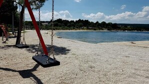 Ein Strand mit einer Schaukel und freiem Blick auf das Wasser.