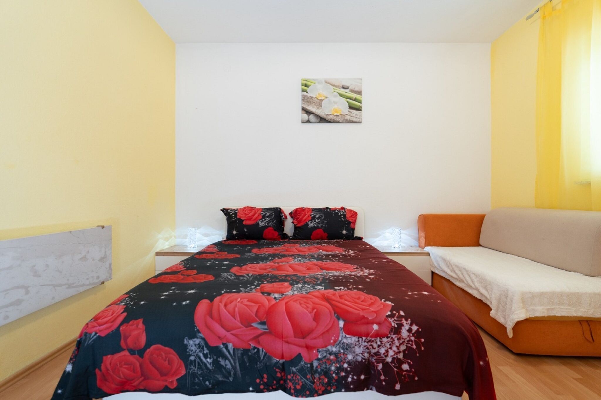 A bedroom with a bed, a sofa, and a small table.
