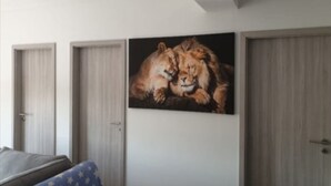 A bedroom with a large painting of a lion, a bed with a blue and white patterned cover, and wooden doors.