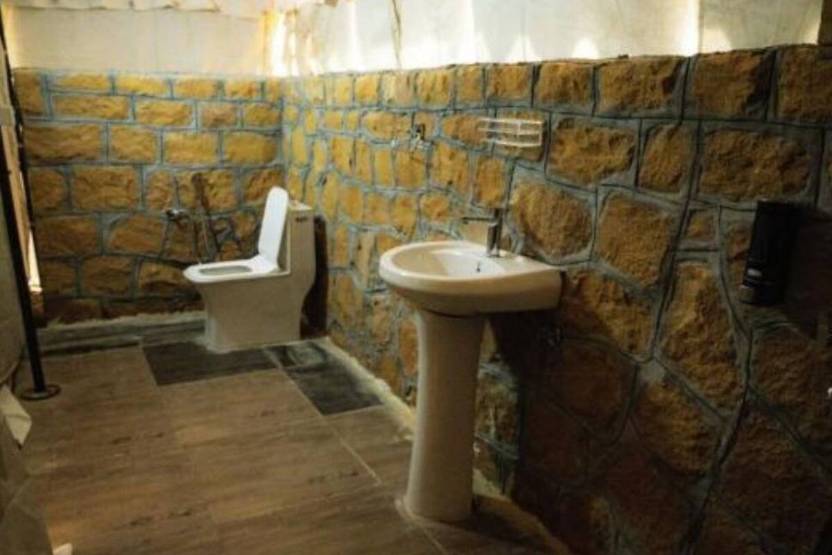 A bathroom with a stone wall, a sink, and a toilet.