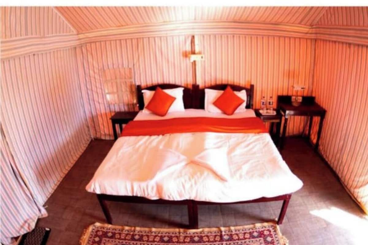A room with a bed, a nightstand, and a lamp.