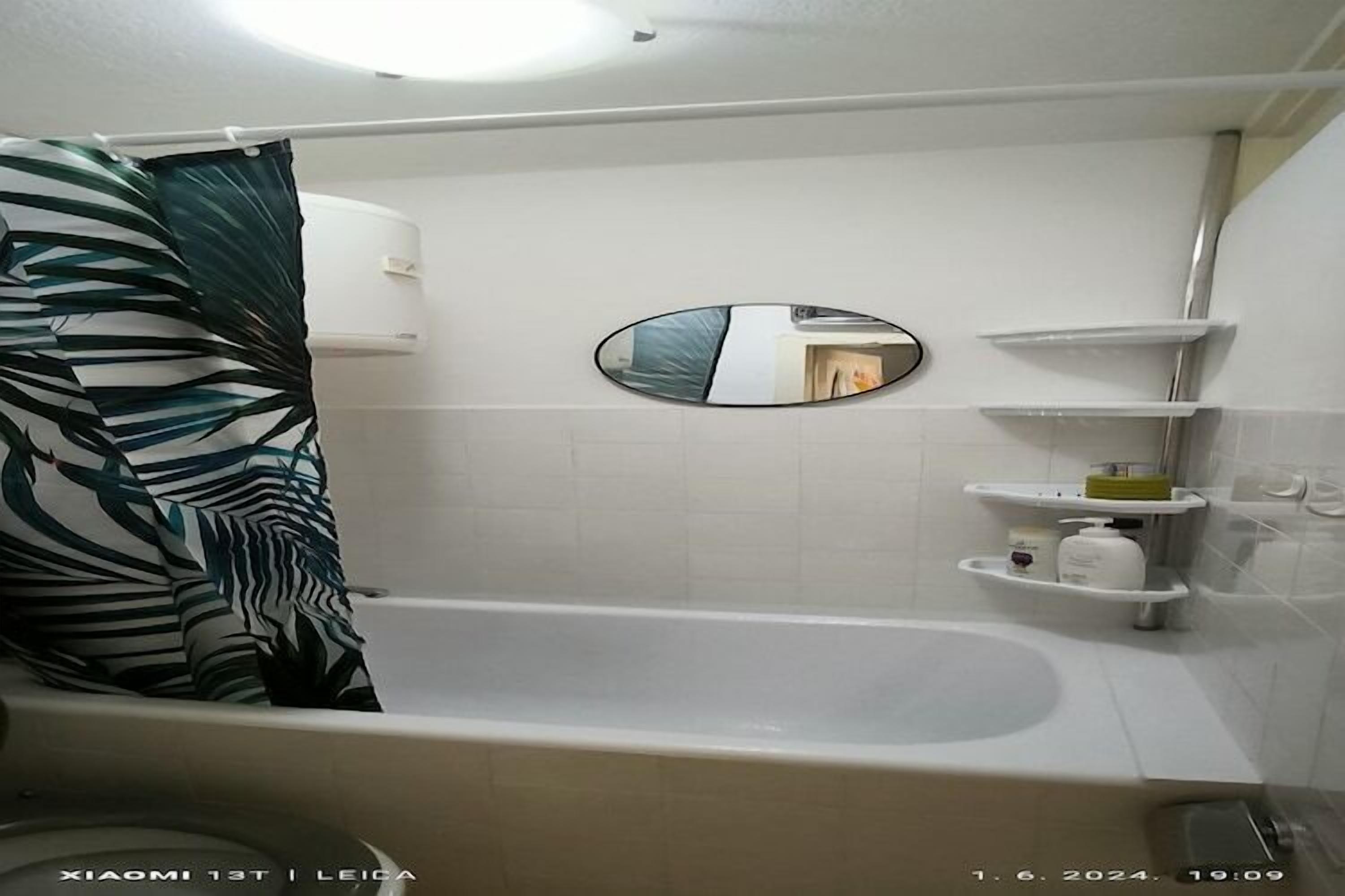 Een badkamer met een bad, een spiegel en planken met toiletartikelen.